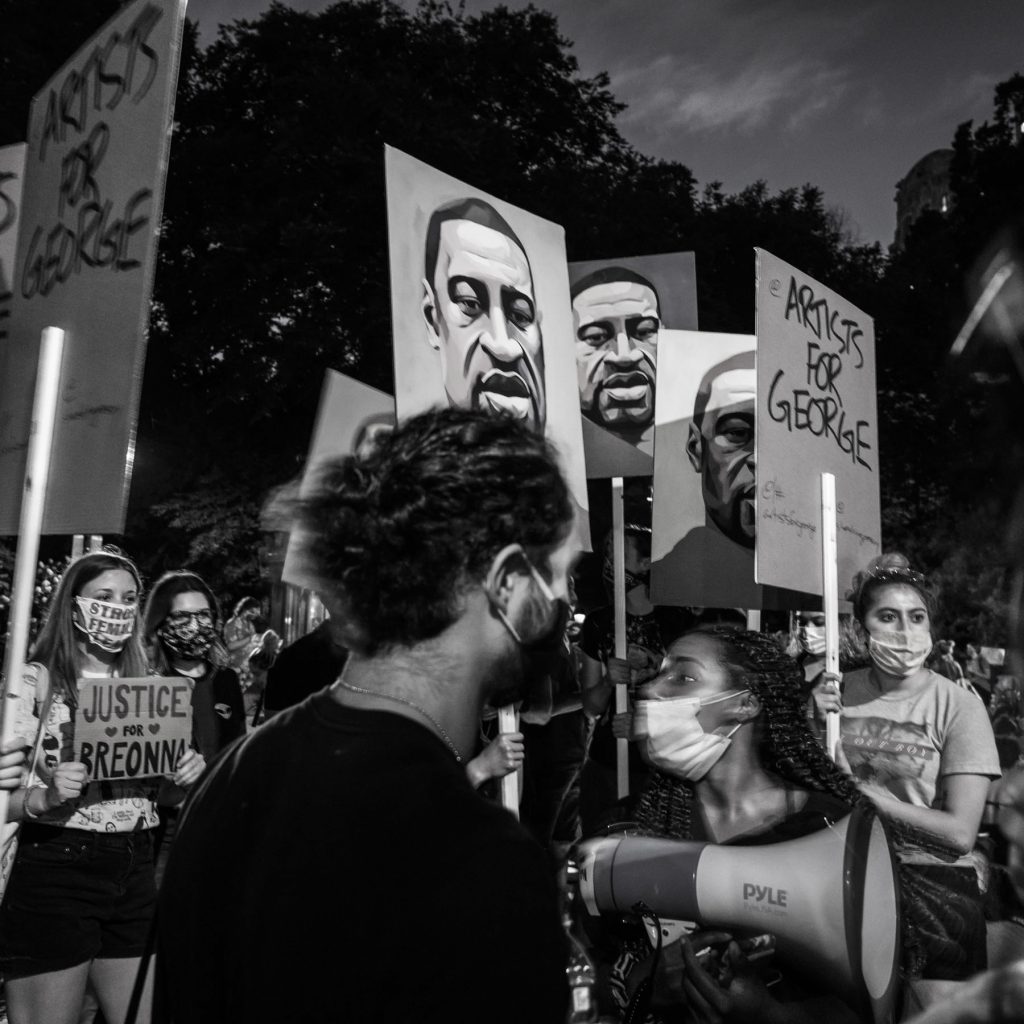 Summer 2020, people holding signs of George Floyd's photo at a protest.